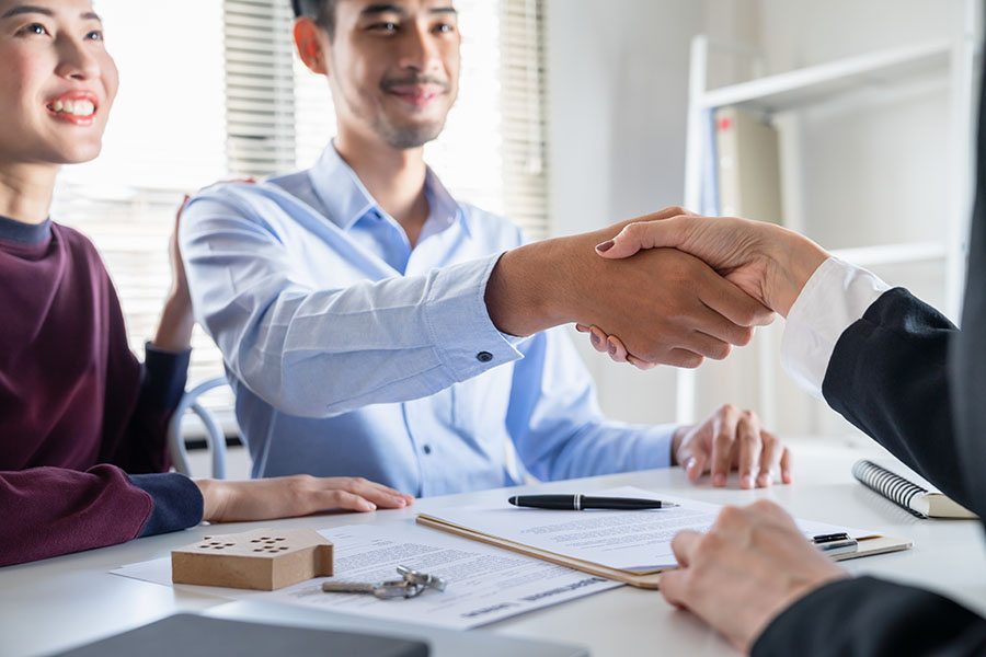 About Our Agency - Young Couple Shaking Hands With Insurance Agent In Office